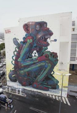 A monkey in shorts and sneakers screeches as he falls apart in this huge street art mural by graffiti artist Aryz