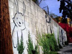A bunny and a bear peek out from between climbing vines in this friendly street art work by Phil Lumbang