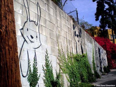 A bunny and a bear peek out from between climbing vines in this friendly street art work by Phil Lumbang