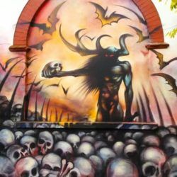 A horned god stands in a hellish graveyard clutching a human skull in this graffiti painting by street artist Jim Vision