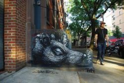 This rat's head lies forever silent beside a road in this artist street art painting by graffiti artist ROA