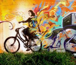 A photograph of a woman riding a bicycle becomes a street art mural by Stinkfish