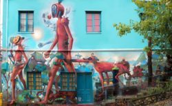 Bizarre humanoid creatures walk through a crazy landscape in this colorful street art mural by Dhear One