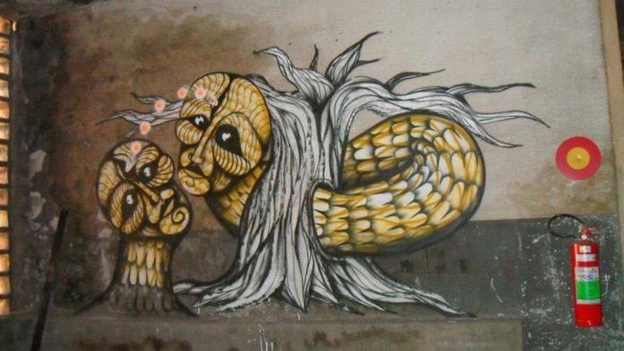 Street artist Dinho Bento paints a mural depicting a scene from the garden of Eden