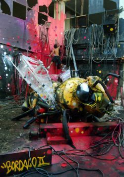 An enormous bee sculpture made out of trash is the central focus of this captivating street art installation by Bordalo