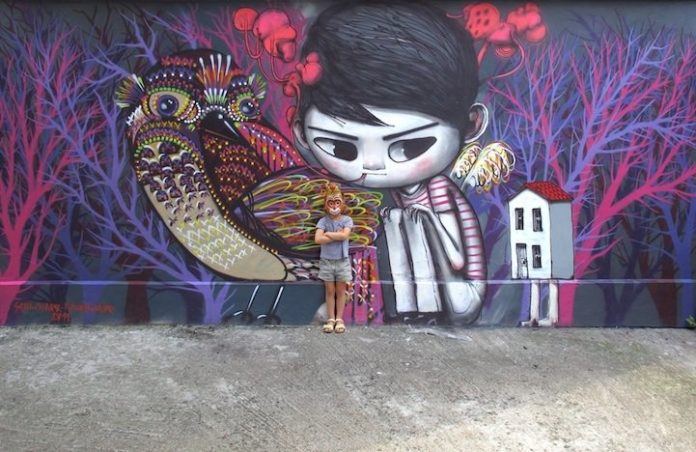 A Parisian boy is surrounded by a dream like forest in this street art mural in France by Seth