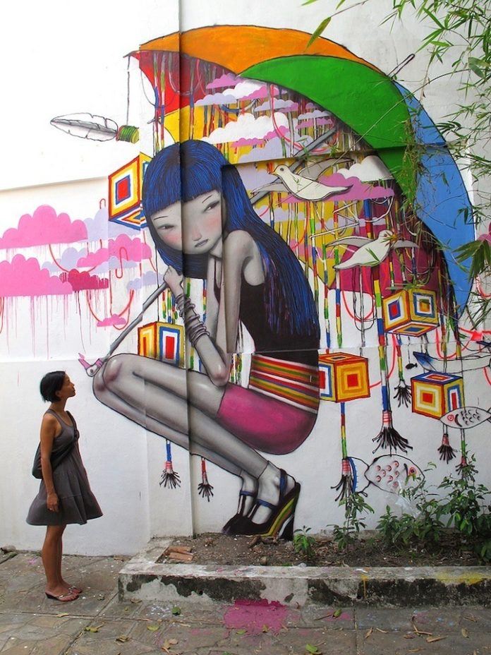 A teenage girl carries an umbrella full of dreams in this colorful street art mural by Seth - in Vietnam