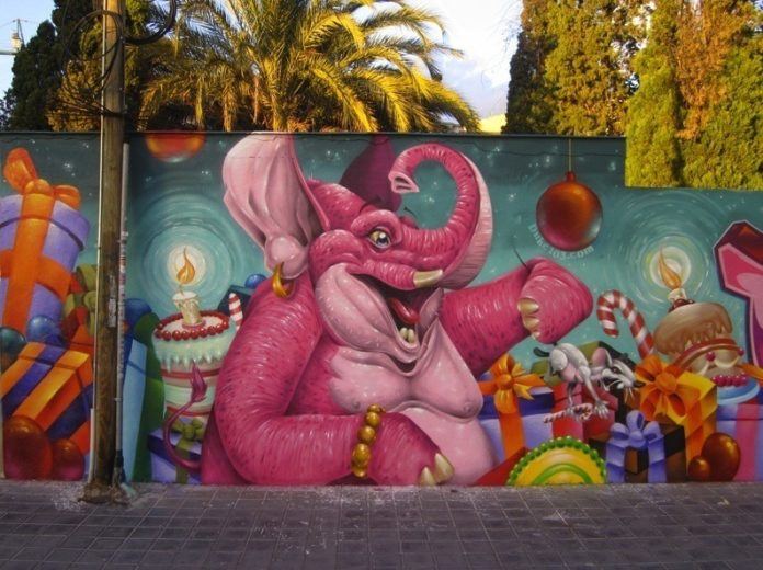 An overexcitable pink elephant celebrates a funny birthday in this colorful street art mural by graffiti artist Duke 103