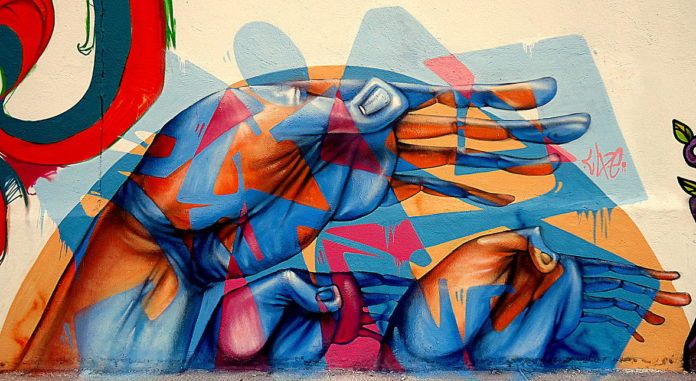 Brazilian graffiti artist Lelin Alves combines abstract shapes and caricaturized human hands to create this symbolic street art mural
