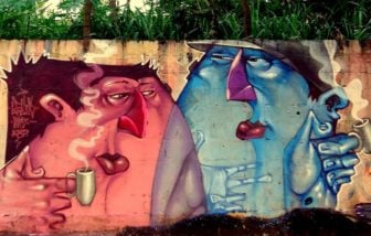Two graffiti characters enjoy a steaming mug of coffee in this street art mural by Lelin Alves