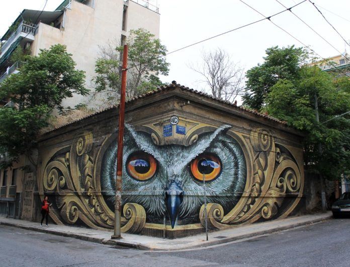 An owl dominates this street corner through this street art mural in Greece by Wild Drawing