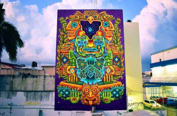 Areúz has covered the side of this big building with a street art mural that depicts animals, men and spirits in the ancient Mayan art style