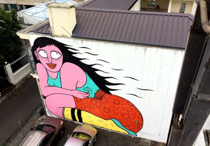 Floe has used bright color paints and bold outlines to create this cartoonish graffiti mural of a beautiful, fleshy woman smiling shyly
