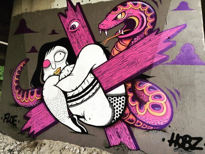 This is a close-up of the collaborative mural painting by Hobz and Floe that shows a woman in lingerie and a hissing snake entangled with a wooden cross