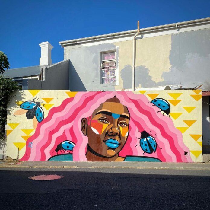 Urban artist Nadia Fisher aka Nardstar has given her garffiti mural girl pink hair and an entourage of African insects